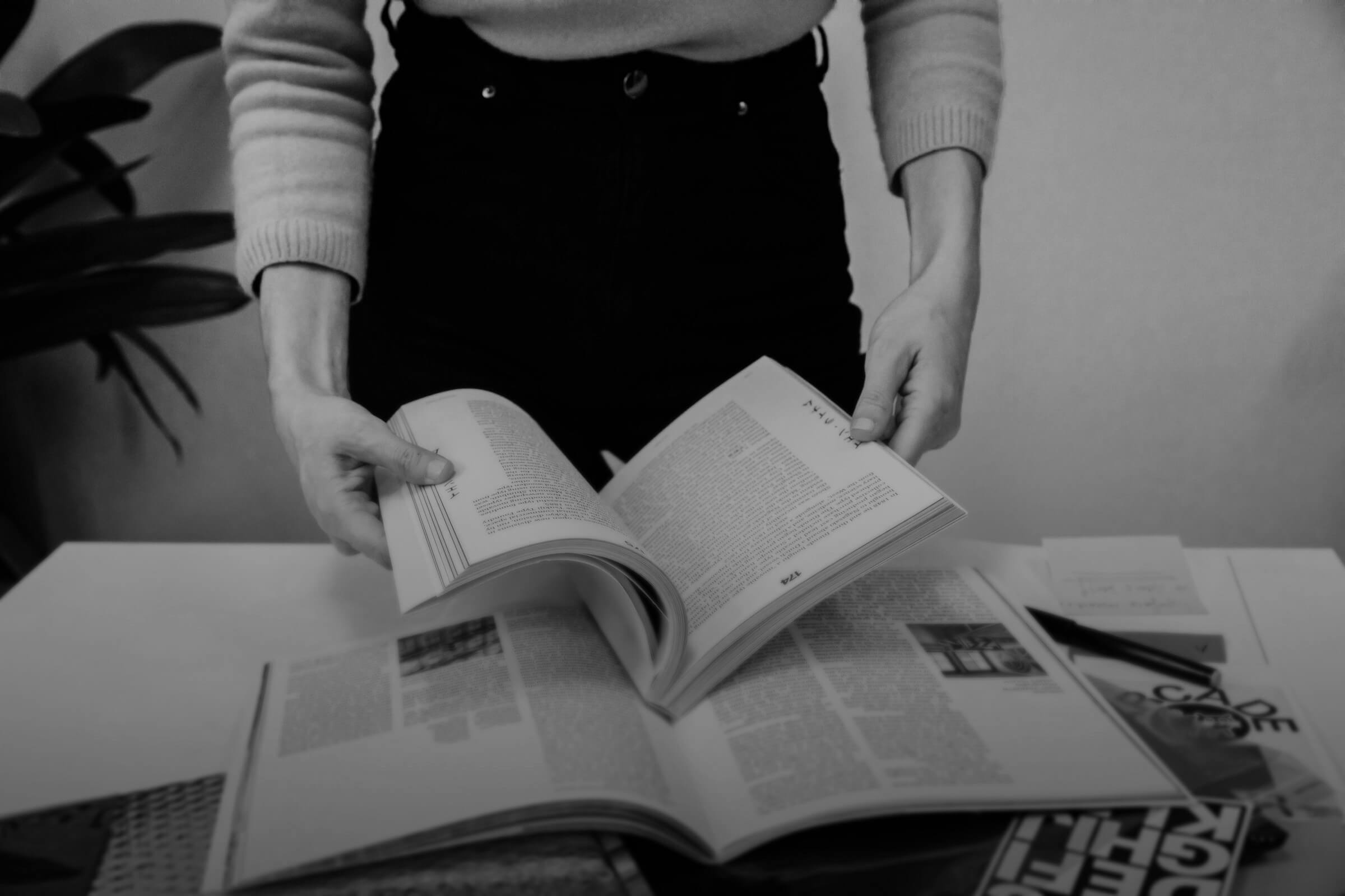 An editor reviewing a set of printed page proofs at a desk